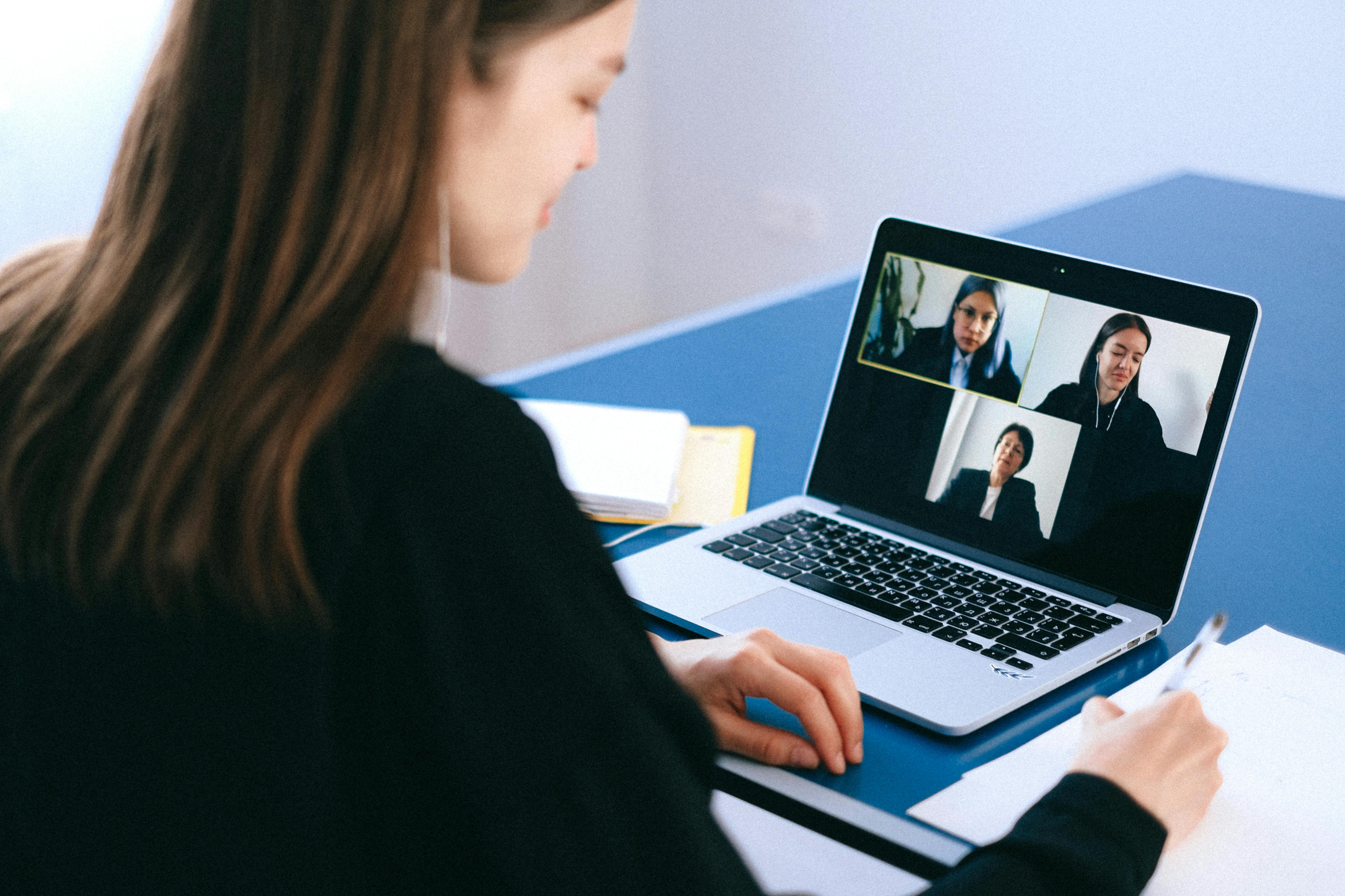 A woman with her laptop open on her desk on a zoom call.