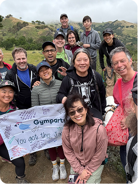 Gymparty group outdoors holding a banner