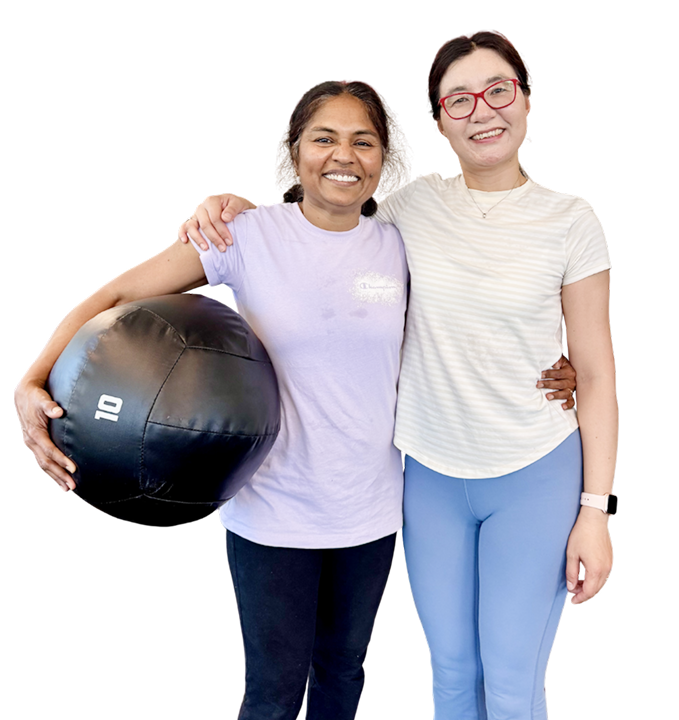 Two smiling Gymparty members standing together, one holding a medicine ball