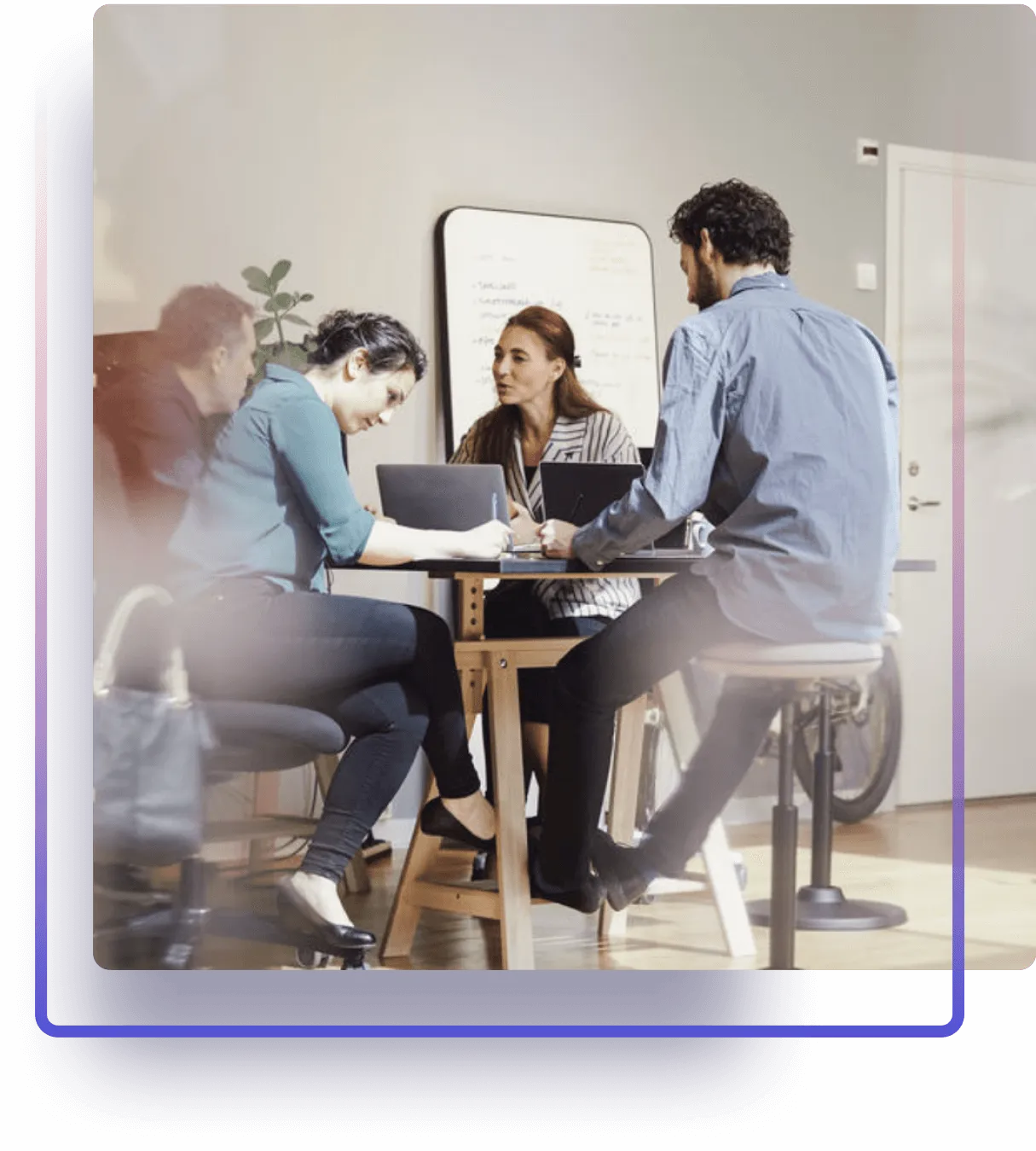 Four colleagues co-working at a desk, purple gradient frame.