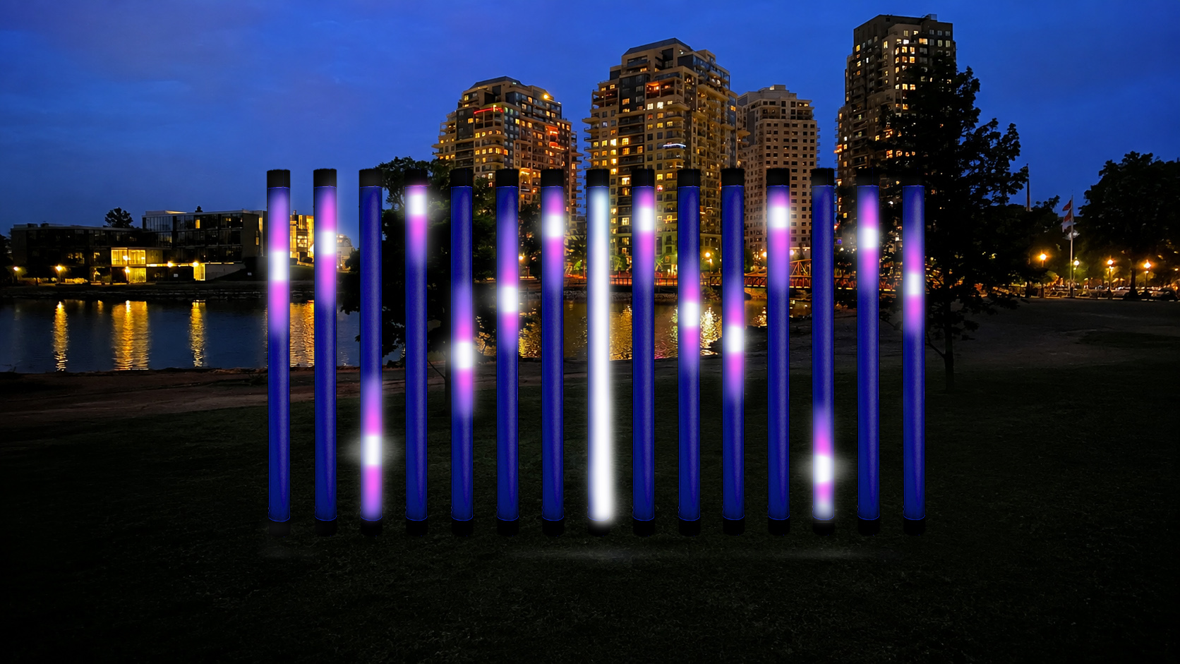 Row of tall vertical light columns glowing purple and white beside a pond, with illuminated high-rise buildings in the background at dusk.
