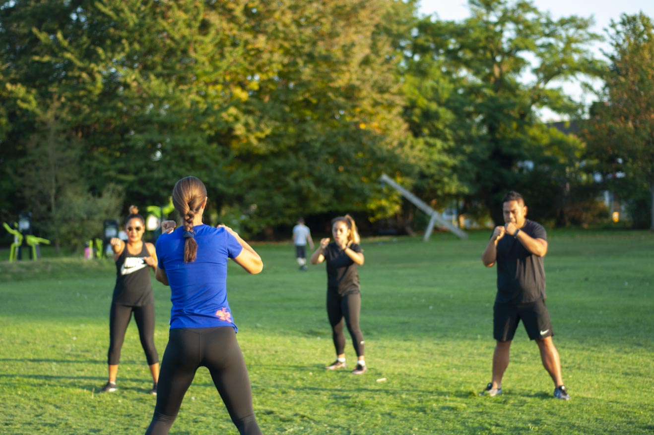 Group class/session with Personal Training doing boxing exercise outdoors in the park