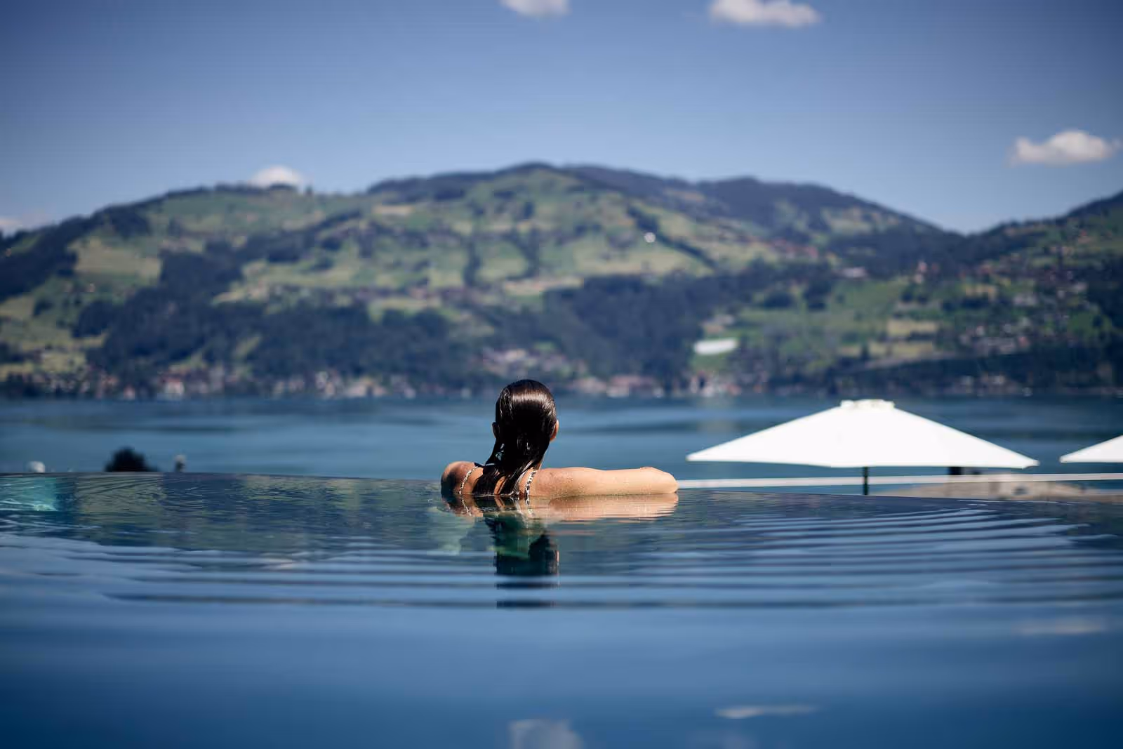 Woman in the infinity pool with view of Lake Thun
