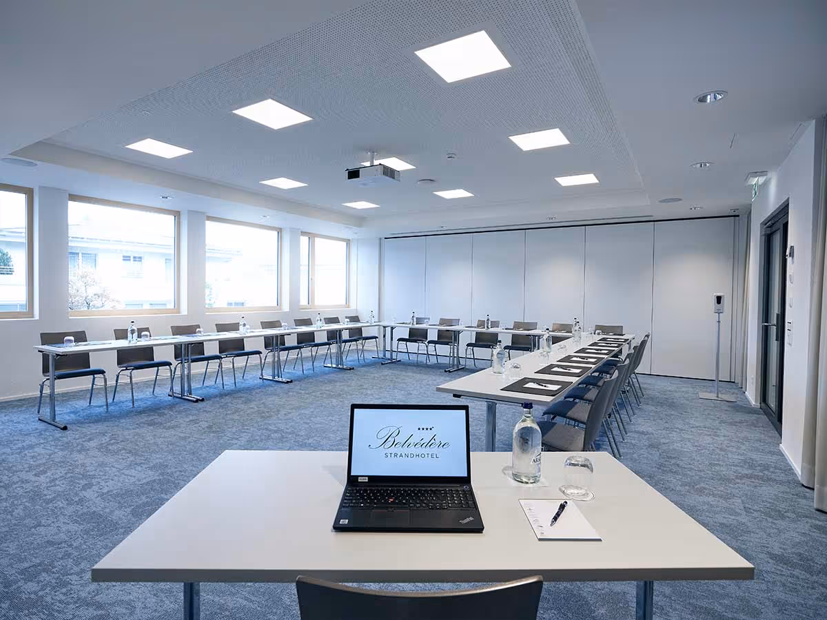 Bright seminar room with U-shaped seating and front desk with laptop