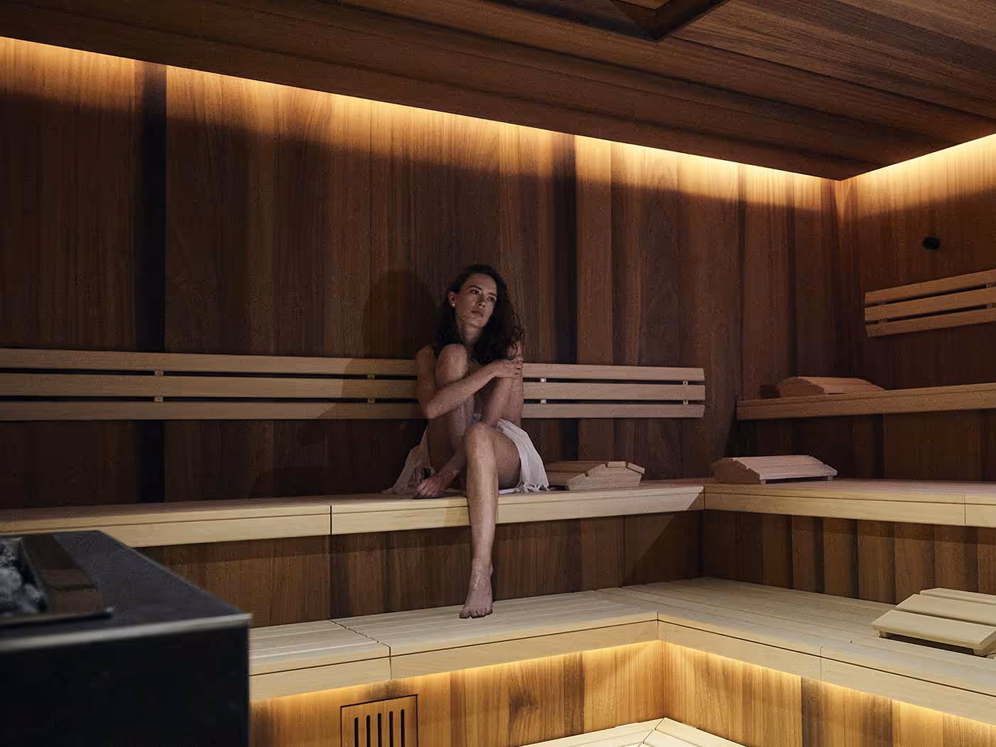 Femme dans un sauna avec poêle dans l'espace bien-être