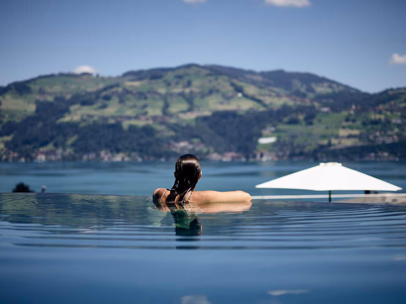 Une femme dans une piscine à débordement regarde le lac de Thoune