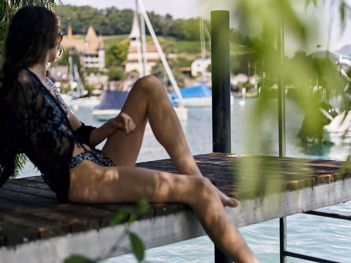 Woman sitting on the jetty and looking out over Spiez Bay