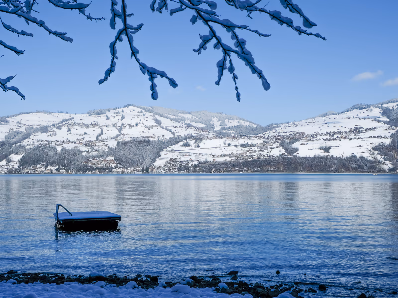 Lake Thun with raft and mountains in the background, snow-covered