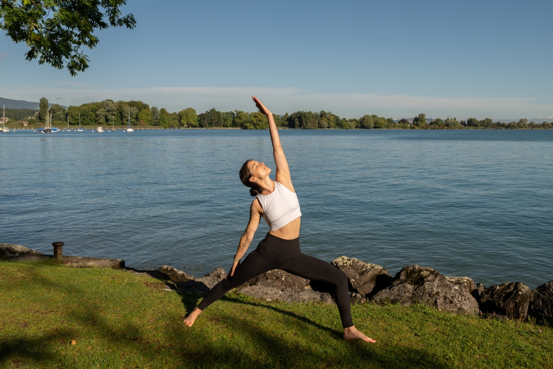 Frau in Yoga Position am Seeufer