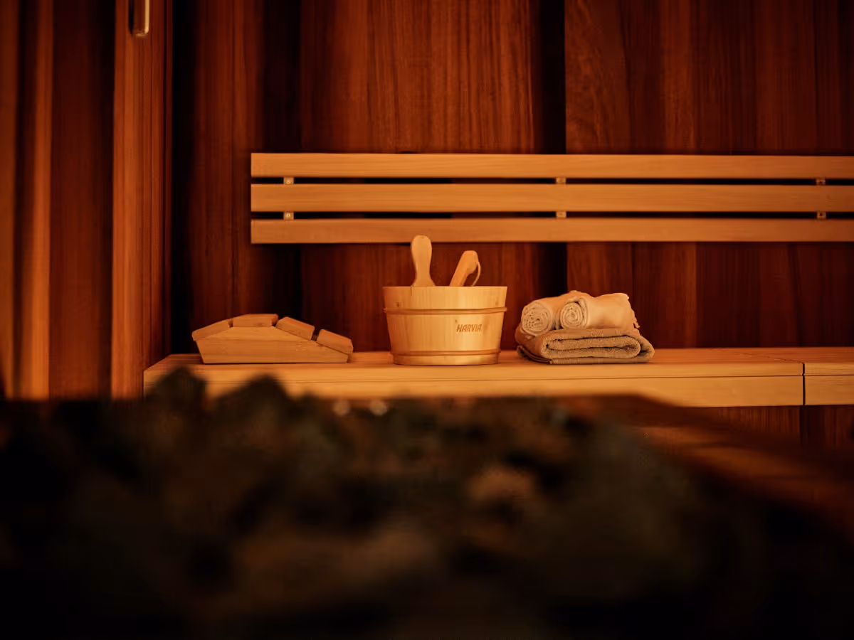 Gemütliche Holzsauna mit warmem Licht, klassischen Aufgussutensilien und entspannter Wellness-Atmosphäre.
