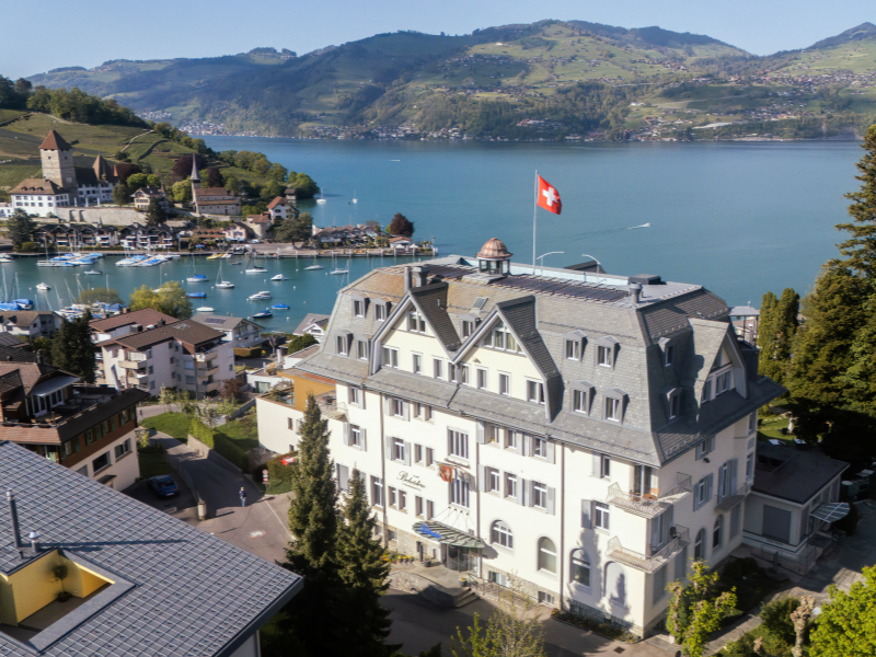 Le bâtiment de l'hôtel vu depuis un drone, avec la baie de Spiez en arrière-plan