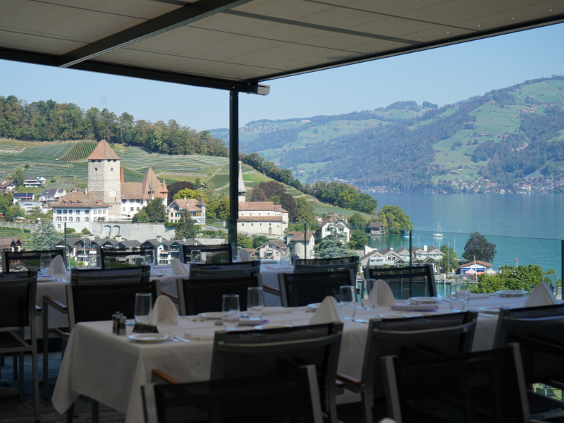 Vue sur la terrasse du restaurant, avec ses tables nappées de blanc et sa vue sur la baie de Spiez
