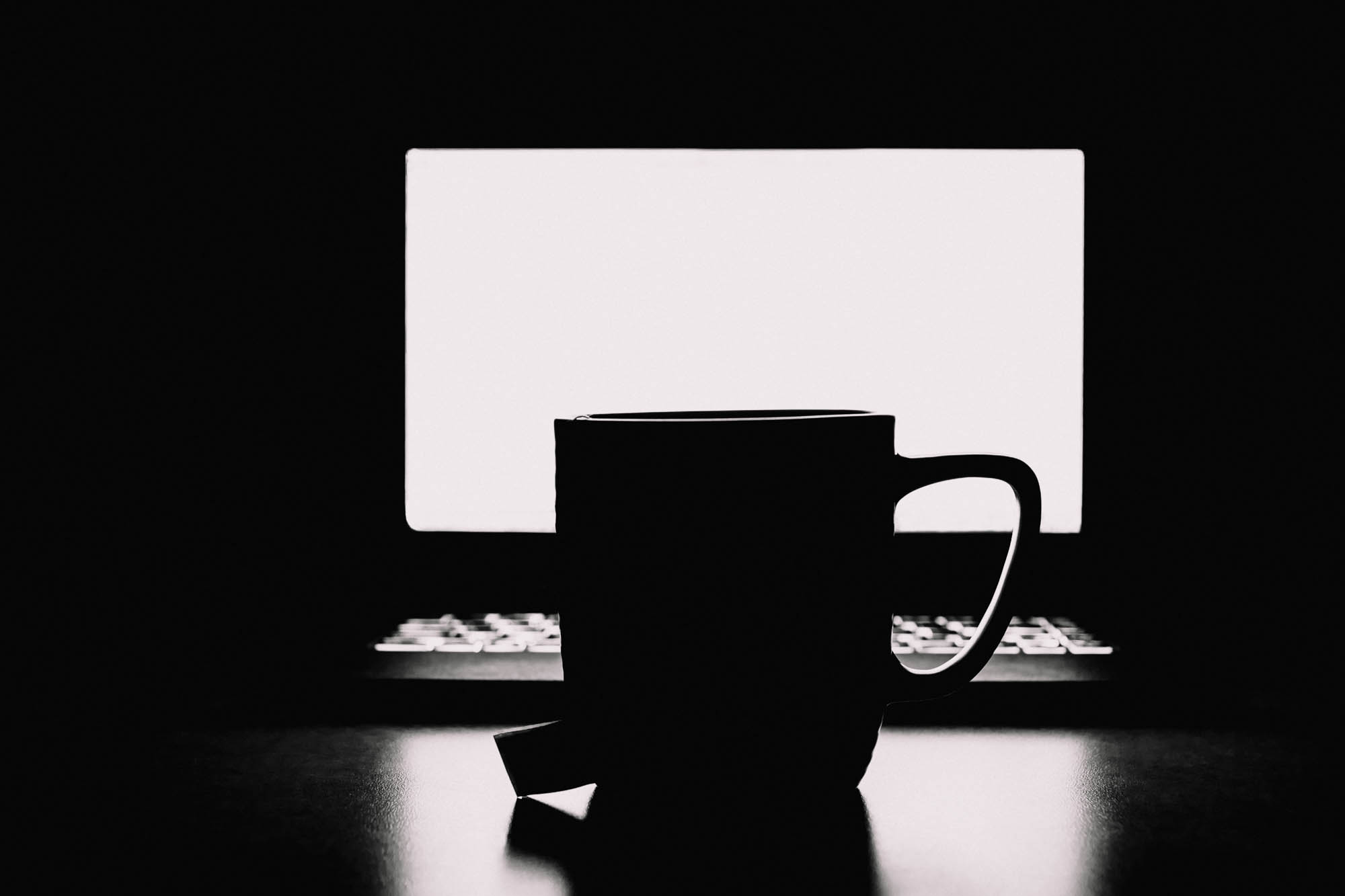 The glow of the computer screen silhouetting a mug