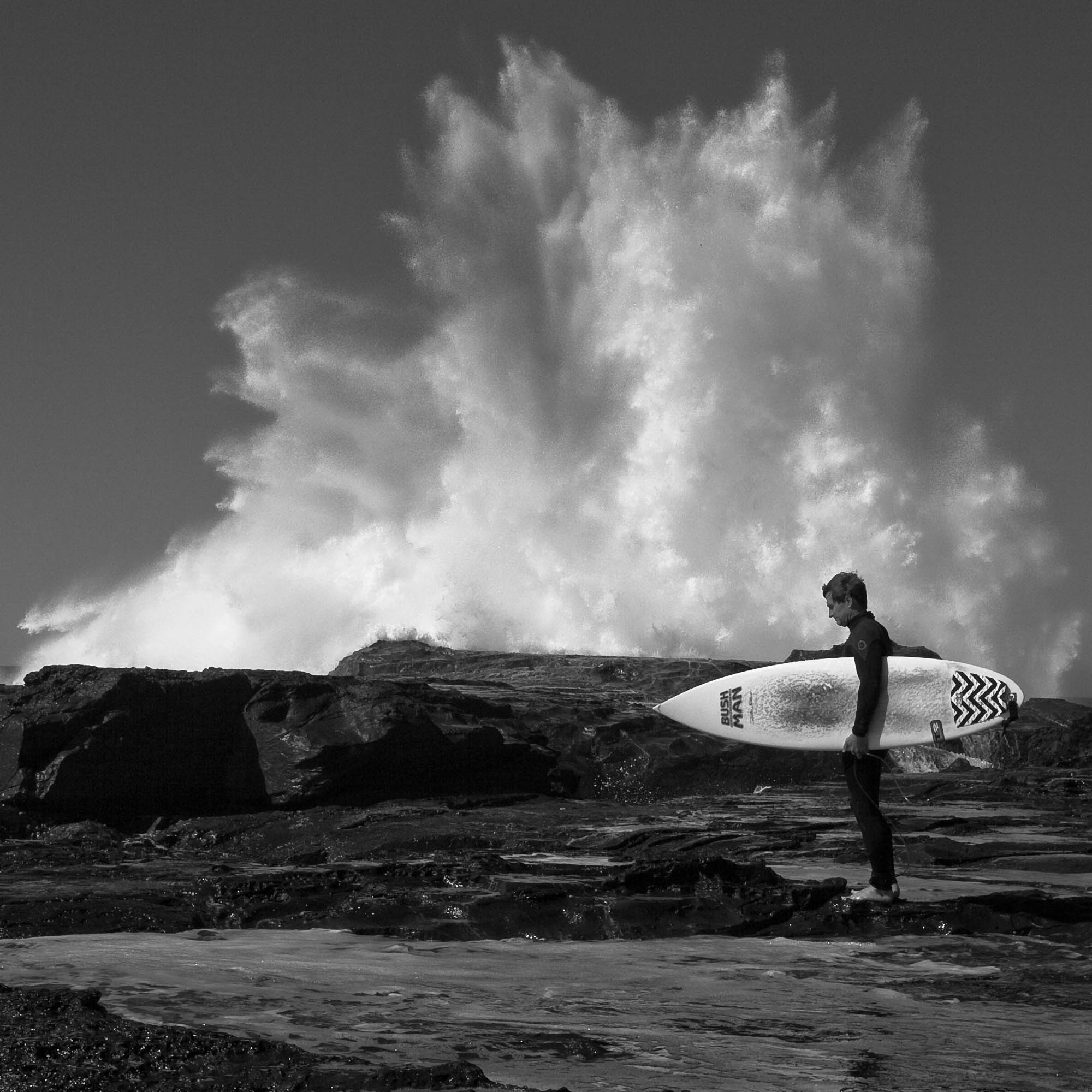 There’s an art in knowing when to stop shooting, in being confident that the shot is in the bag. Black and white photo of a surfer