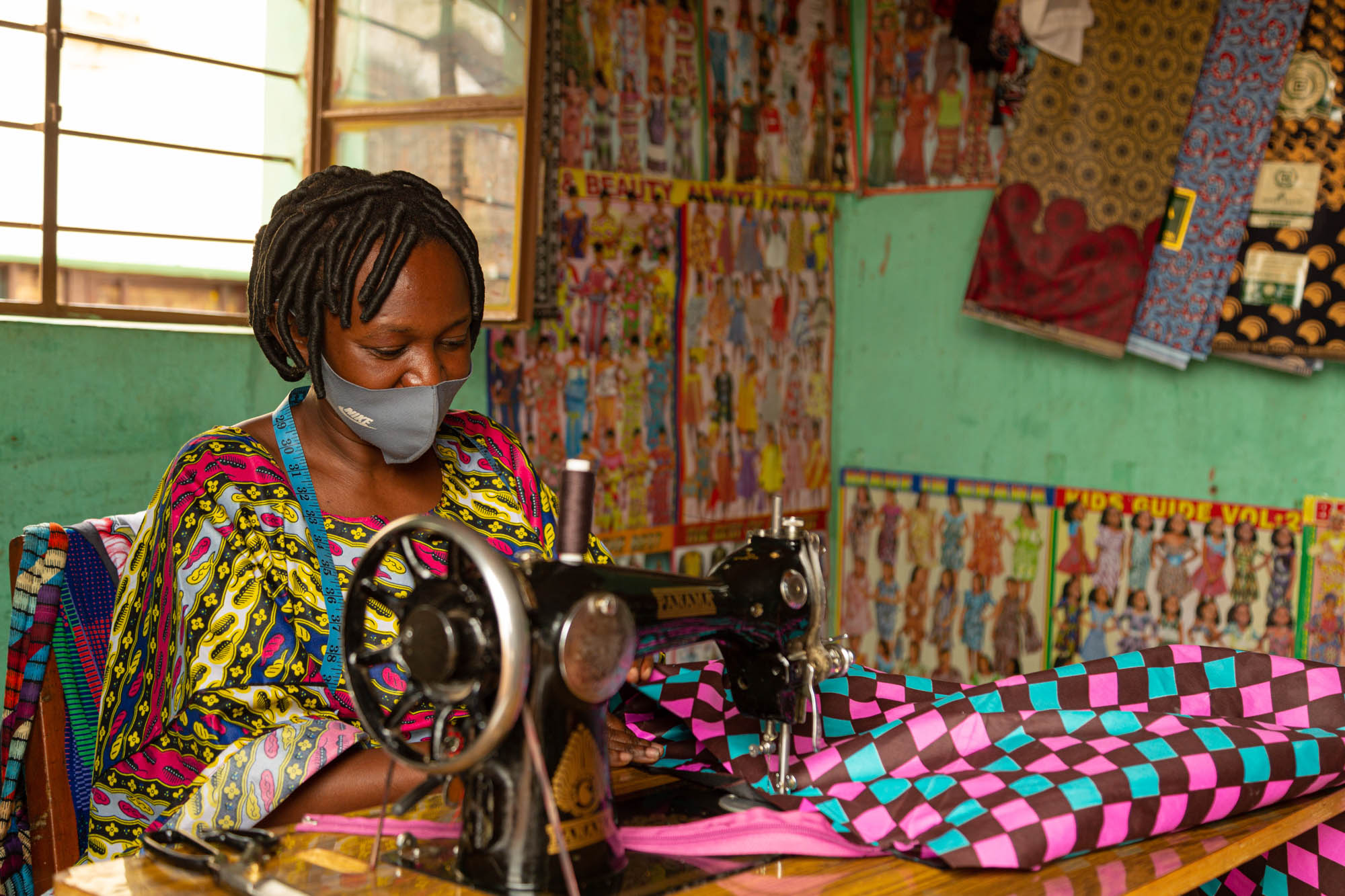 An environmental portrait of a tailor making a bag on her sewing machine. This image was captured in Nyamirambo, Kigali.