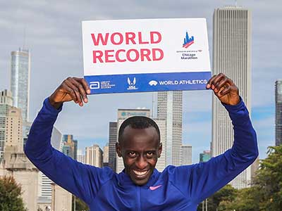 Kelvin Kiptum holds up a world record sign after his win in Chicago in 2023