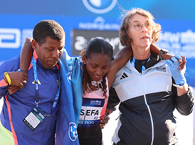 Tigst Assefa is helped away from the finish line