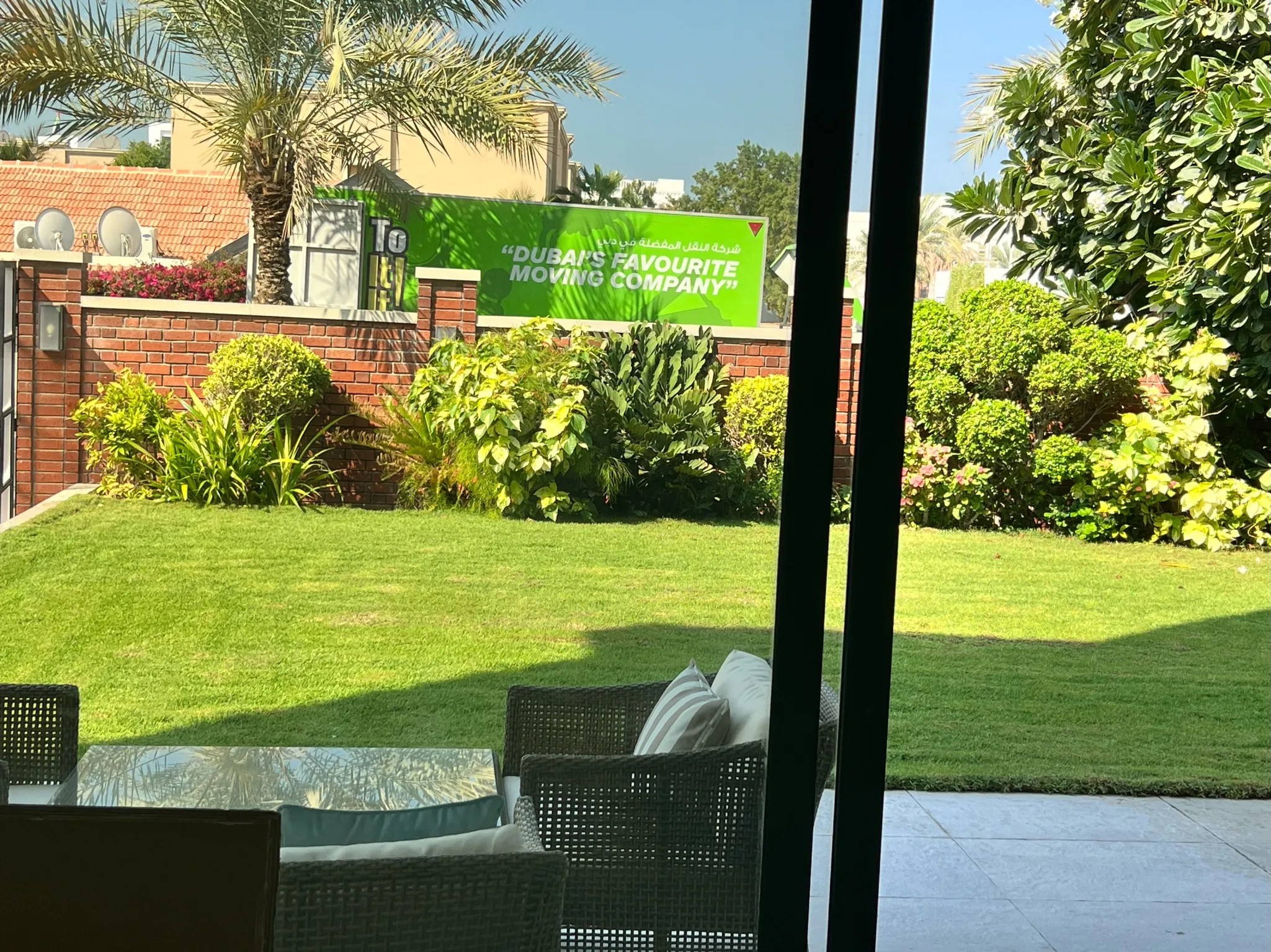 Patio view across a garden lawn to an I Like To Move It Move It removal truck parked on the road outside