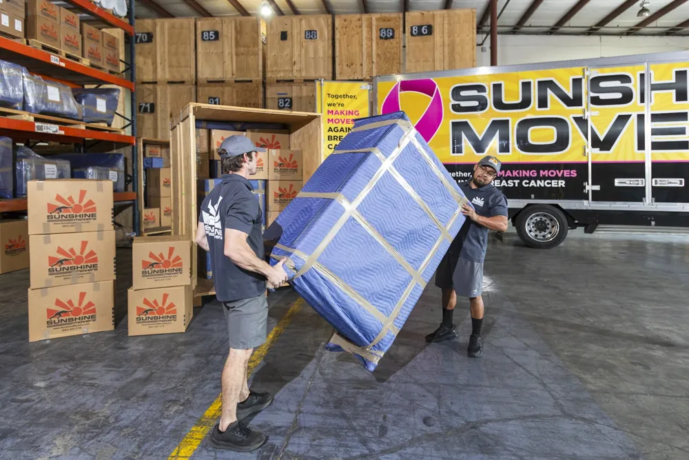 Movers wrapping furniture with protective blankets before storage