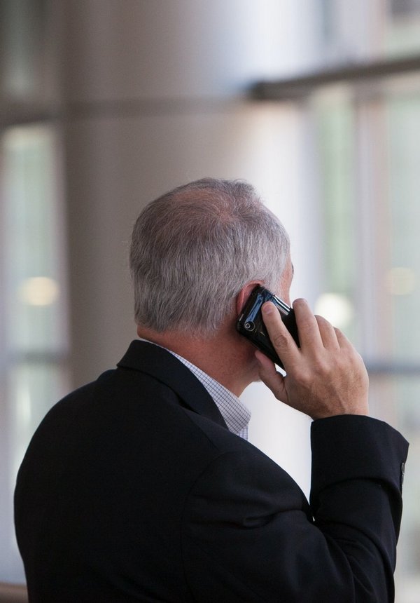 Man holding smartphone in front of a windowpane.