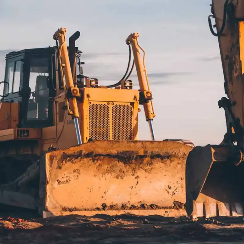 Wheel loader 644J inside service bay; scraped bucket and massive treaded tires ready for maintenance.
