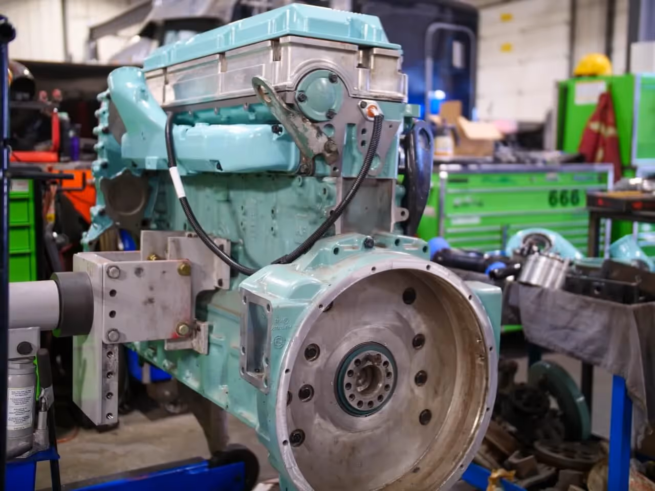 Diesel engine rebuild in progress with exposed flywheel housing inside a heavy-duty repair workshop.