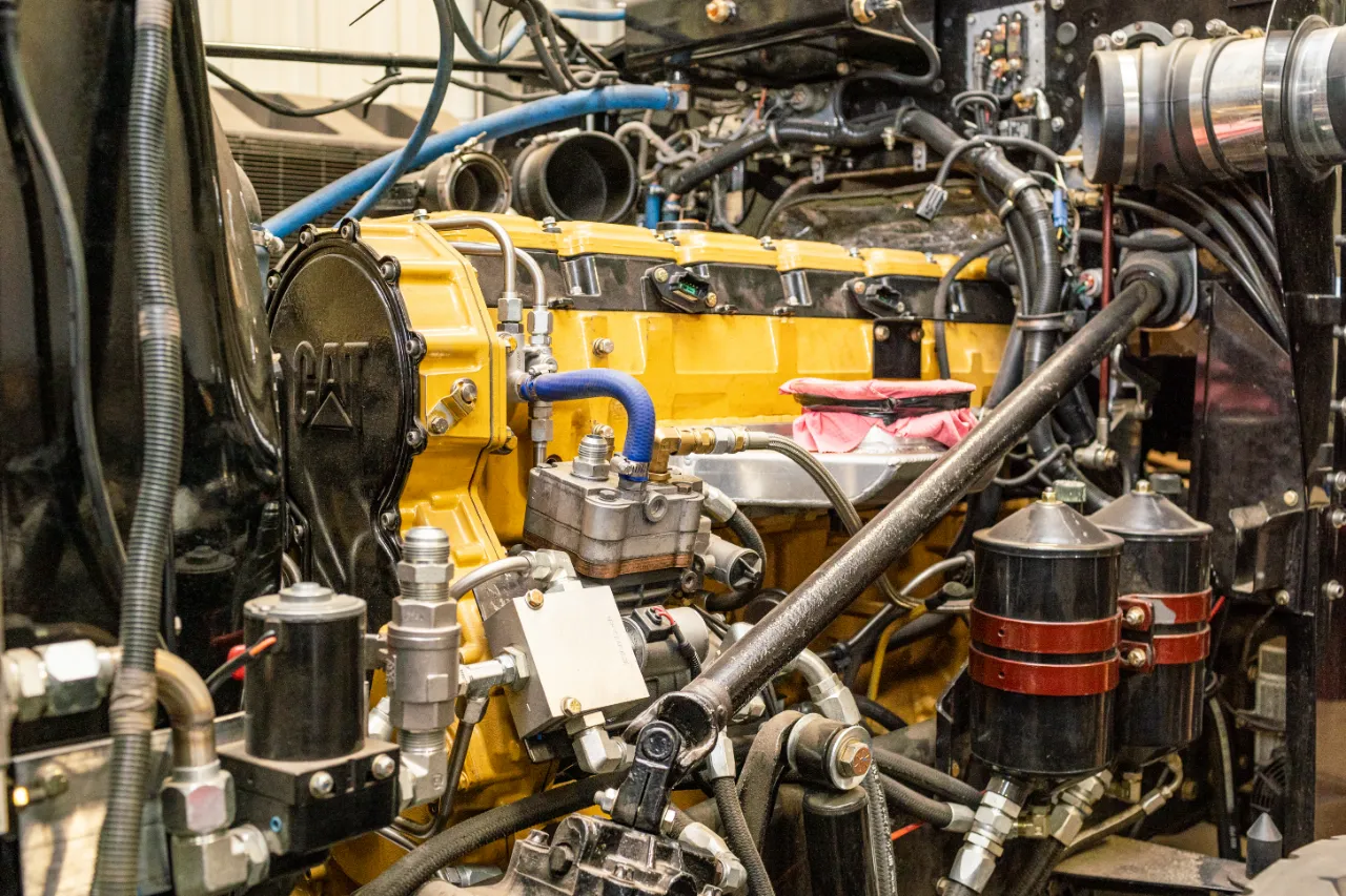 CAT diesel engine assembly in a heavy-duty truck showing fuel filters, hoses, and hydraulic components.