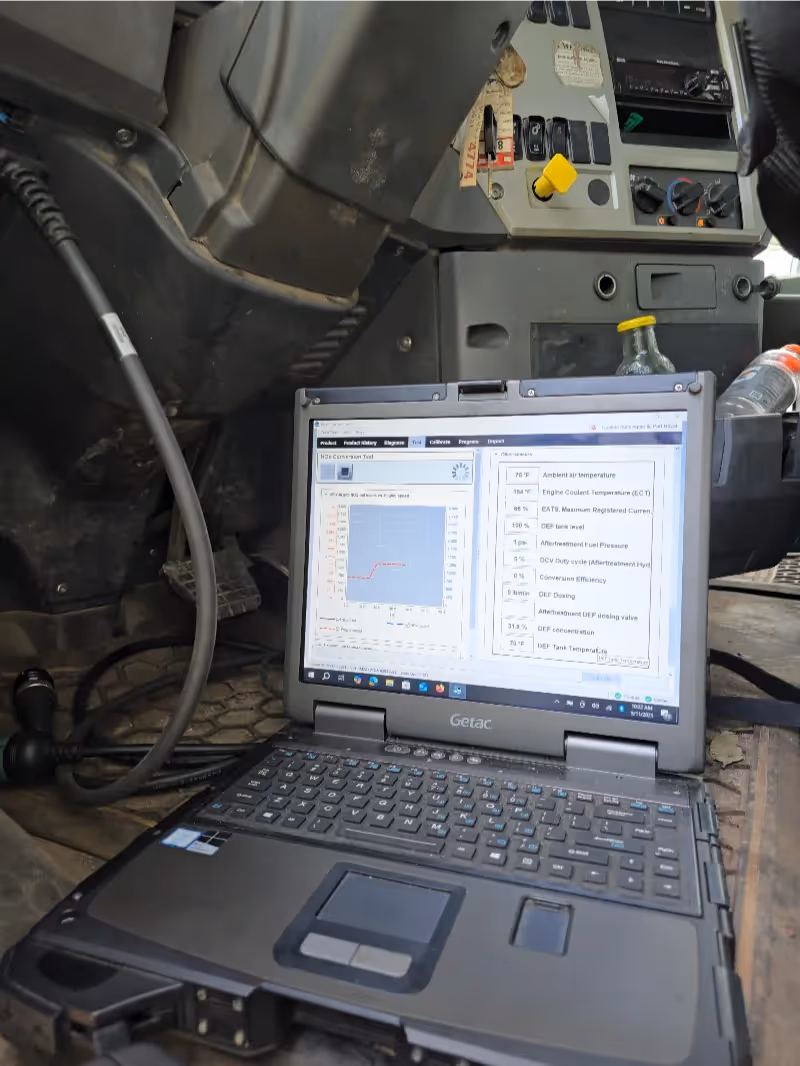 Aftertreatment diagnostics with Getac laptop running “NOx Conversion Test” inside heavy-duty truck cab.