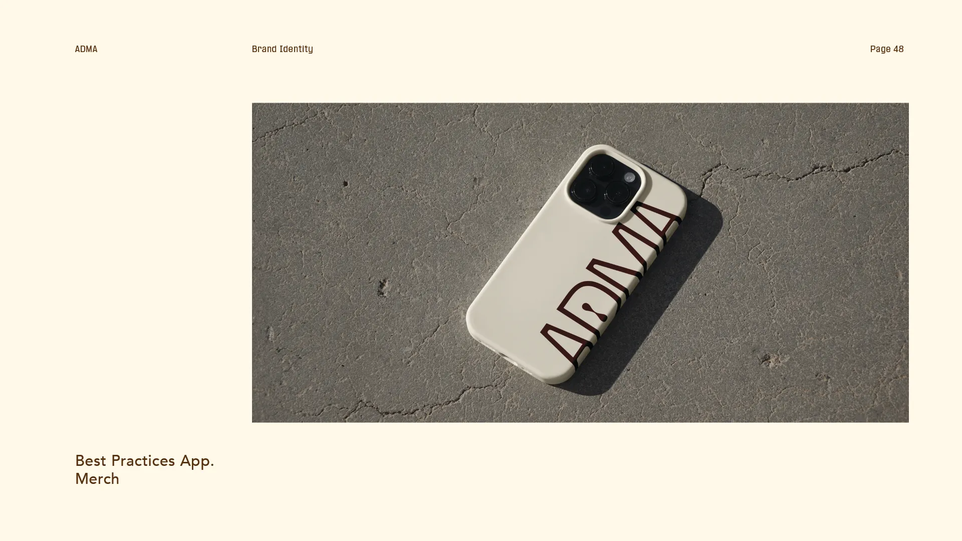 Cream-colored phone case with large brown letters spelling ADMA lying on cracked concrete surface.