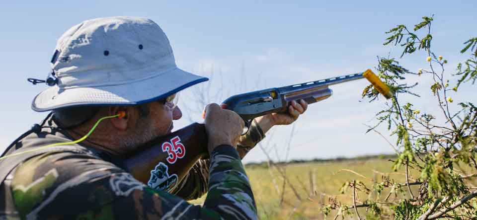 Hunter in a wide-brim hat shooting at doves