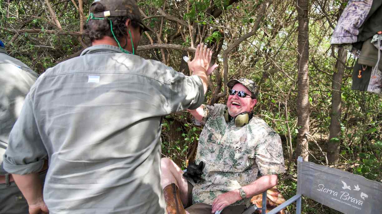 Hunting guide high-fiving guests in the field