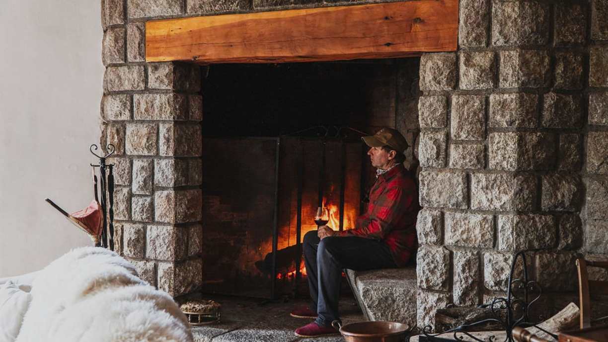 Guest by the stone fireplace at Bravo Sur Lodge