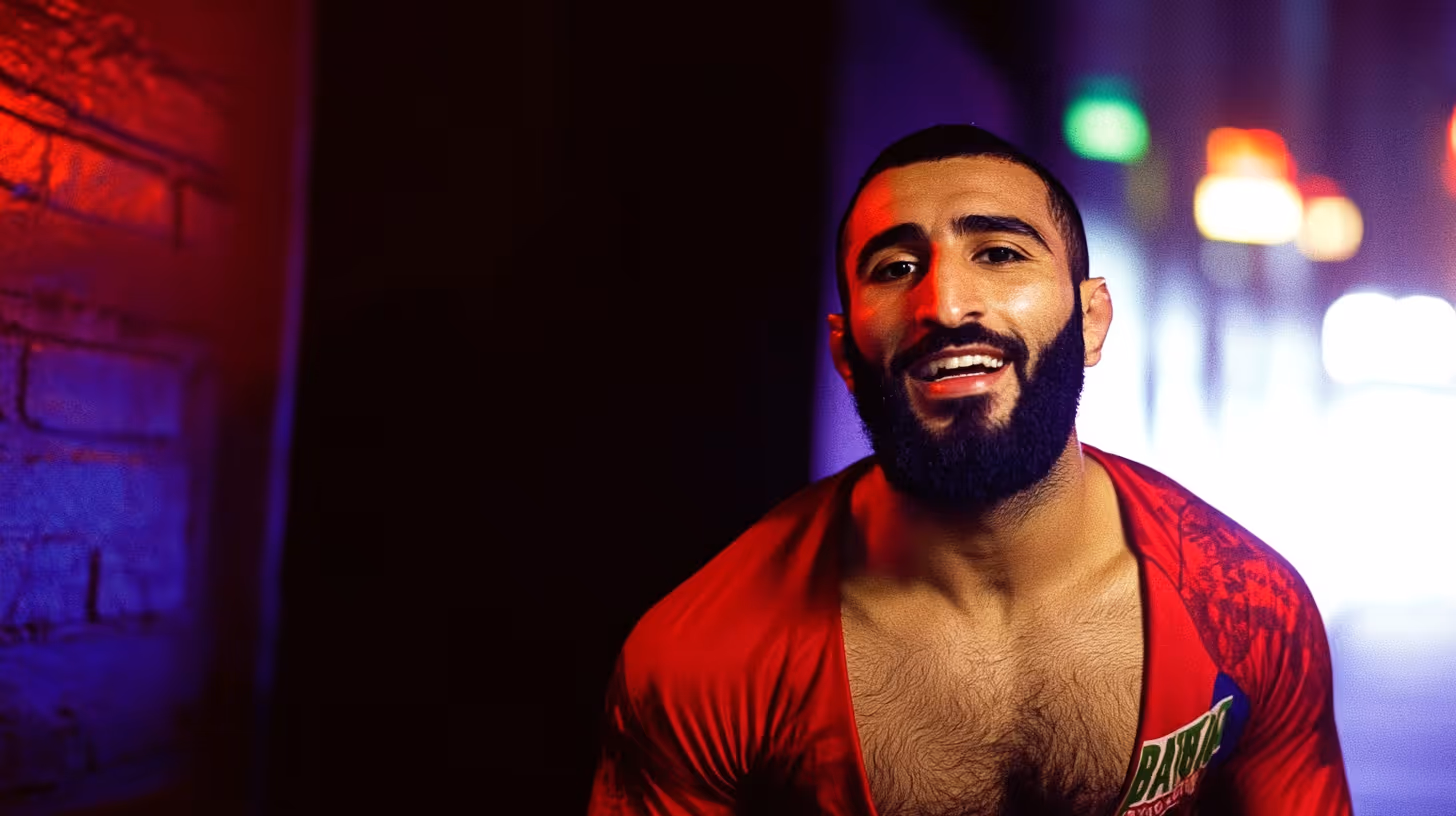 Belal Muhammad in a red shirt shows off his muscular build and a beaming smile in a dynamic pose under dramatic colored gym lights.