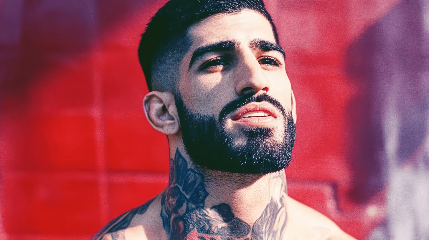 Ilia Topuria MMA fighter, shirtless with detailed neck and chest tattoos, confident and focused against a vibrant red wall.