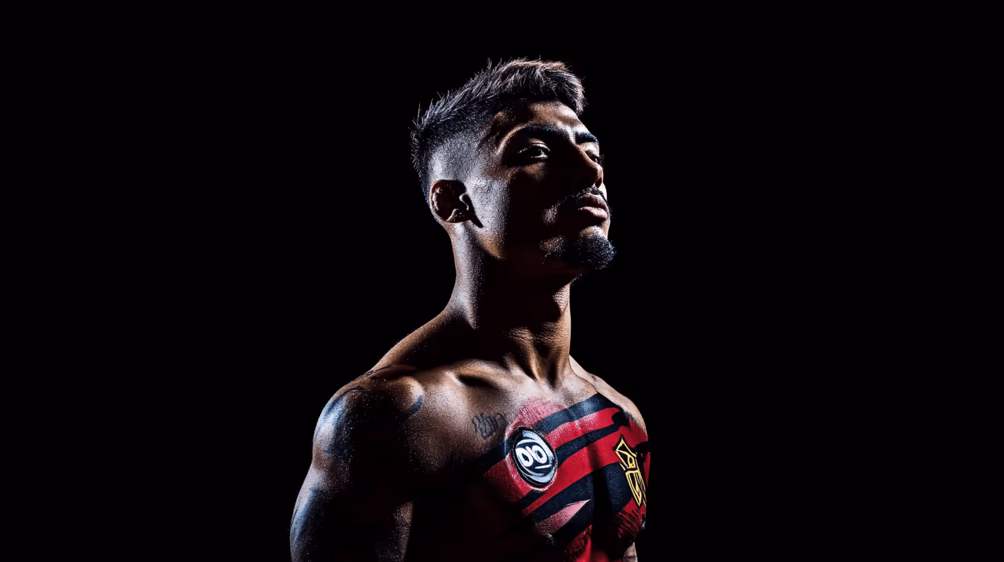 MMA fighter in a dramatic side pose with exposed, tattooed chest and vibrant red design against a black backdrop.
