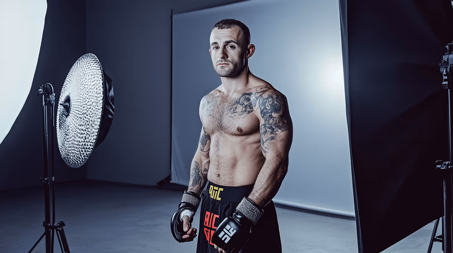 Alexander Volkanovski strikes a confident pose, showcasing his muscular, tattooed torso with black shorts and gloves in studio lighting.
