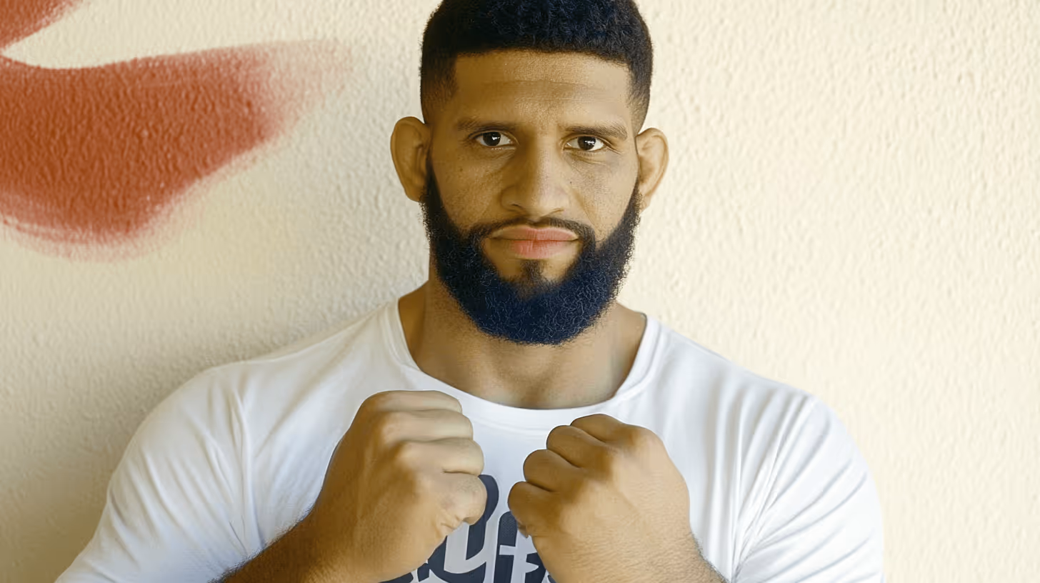 MMA fighter Waldo Cortes-Acosta in a combative stance with raised fists, focused expression, white shirt, and red-accented wall.