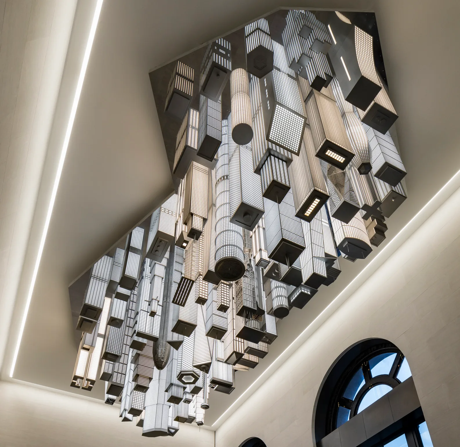 A photograph of "The Hive," a public art work by Elmgreen & Dragnet that depicts a scaled architectural model of a global metropolis suspended from the ceiling of Moynihan Station's 31st Street Entrance Hall.