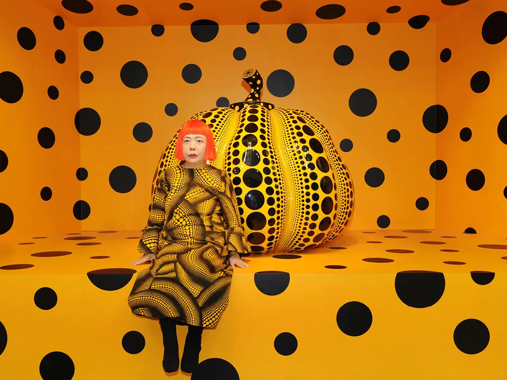 A woman sitting in front of a large pumpkin, entire scene decorated with black polka dots on orange background