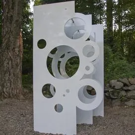 Image of installation of white material with circle holes installed in a forest
