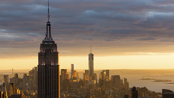 Picture of downtown Manhattan skyline with a dramatic sunset with yellows and blues.