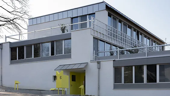 Image of the Therwil Terraced House, a two story white house with bands of windows on both sides.