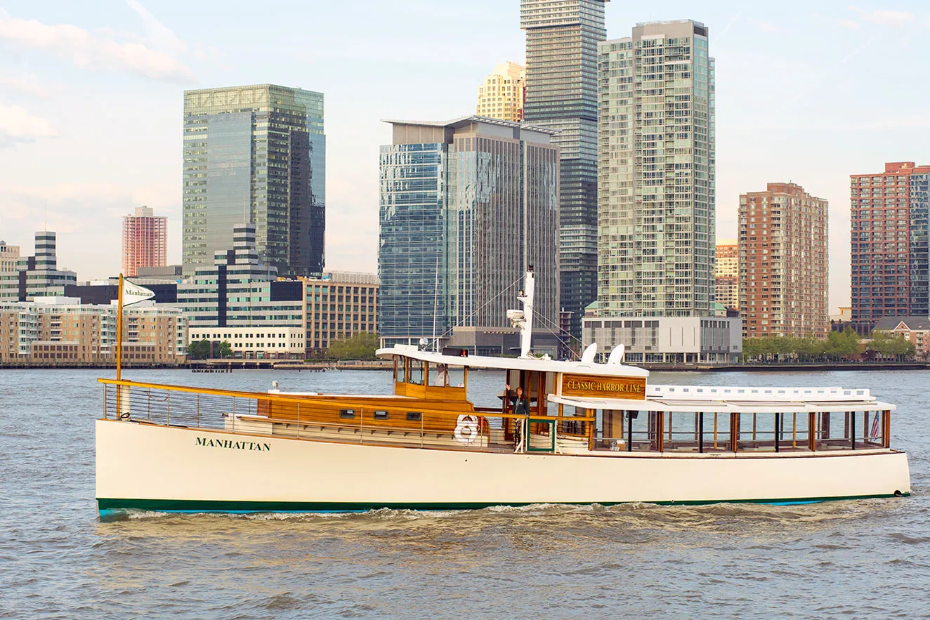 A 1920s style yacht on the river in front of the NYC skyline