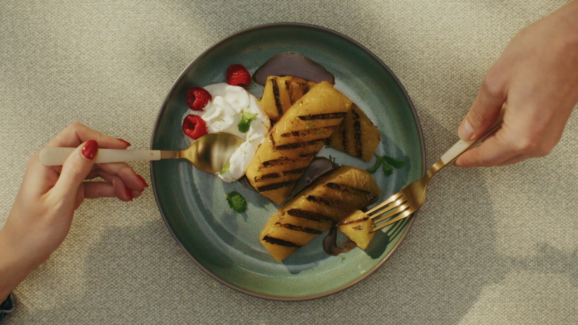 Overhead single seared scallop in its shell with lemon zest and dill butter, on a blue plate on wood.