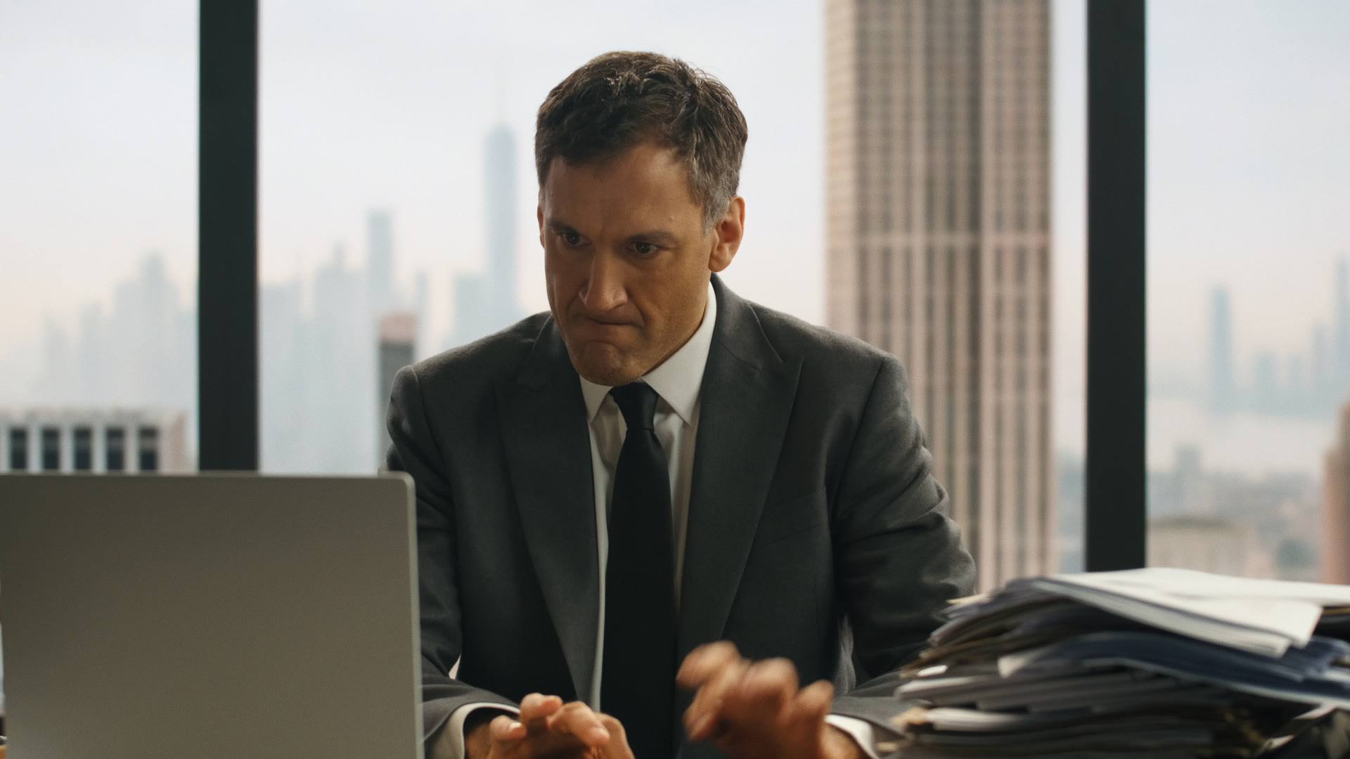 Mid-shot of the lawyer hovering hands tensely over the keyboard, full NYC skyline VP plate behind.
