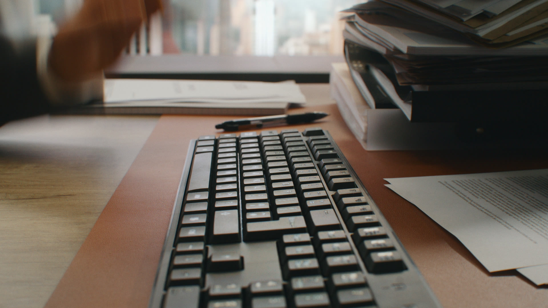 Low-angle hand-on-keyboard close-up: lawyer's hands tap a black keyboard mid-search.
