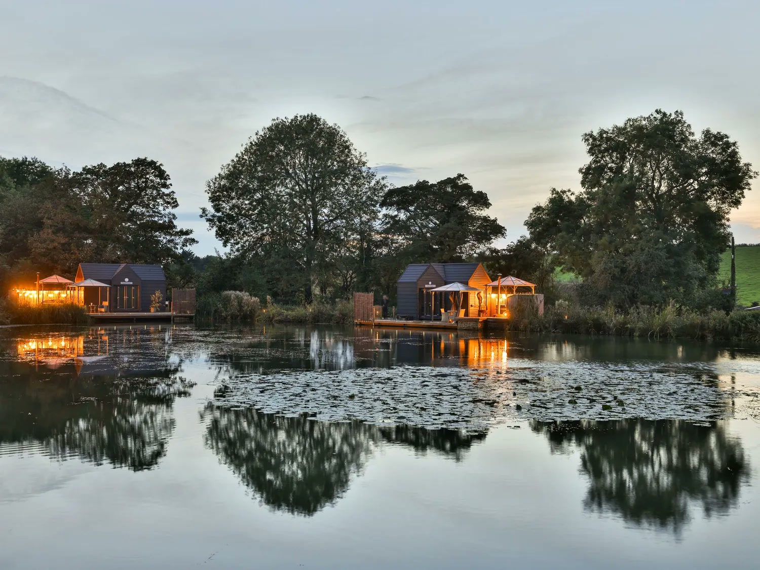 AI-generated reference image of warmly lit lakeside lodges reflected in still water