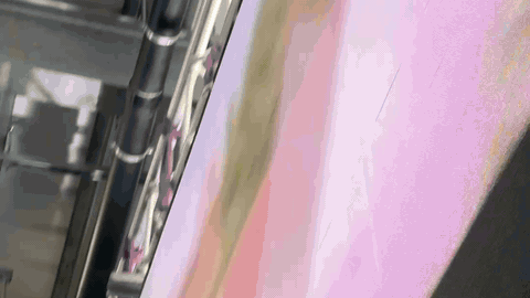 BTS look-up between the train carriage and the LED panel volume — magenta sky plate rendering live on the panels, lighting unit and cabling overhead, panel scaffolding in frame