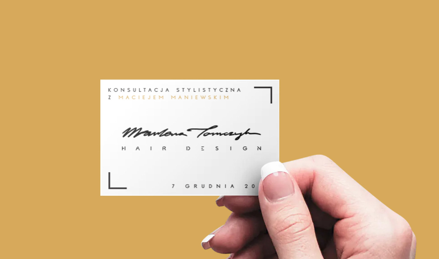 Biała wizytówka z czarnym logotypem Marlena Tomczyk Hair Design, trzymana w dłoni na tle złotego koloru – element identyfikacji wizualnej w projekcie Outletando.