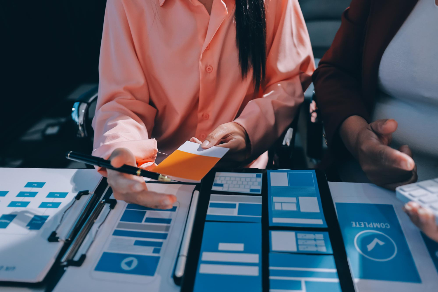 Zespół projektowy omawia makietę strony internetowej, wybierając kolory i układ elementów interfejsu.